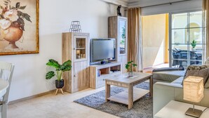 A modern living room with a television, wooden cabinet, and a sofa. - Bright 2-Bed Apartment in Estepona's Peaceful Puerto Alto with Pools and Terrace (Estepona)