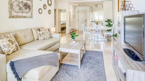 A modern living room with a sofa, coffee table, TV, and dining area. - Bright 2-Bed Apartment in Estepona's Peaceful Puerto Alto with Pools and Terrace (Estepona)