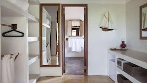 Un couloir avec un miroir, une décoration représentant un voilier suspendu et une étagère avec des serviettes pliées.