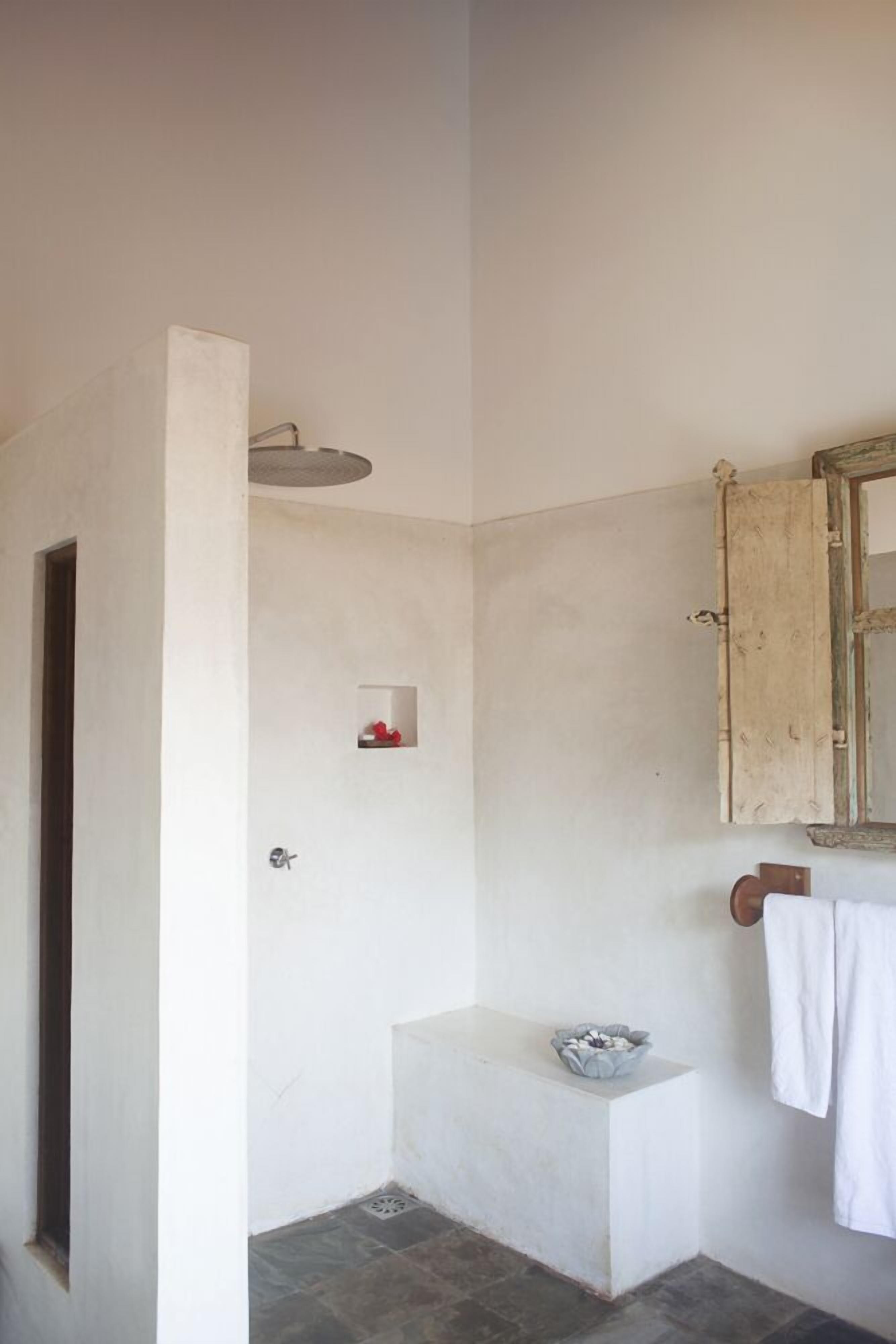 A bathroom with a shower, a small sink, and a towel hanging on the wall.