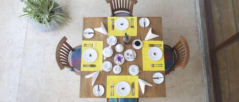 A dining table set for four with yellow placemats, white plates, and cutlery.