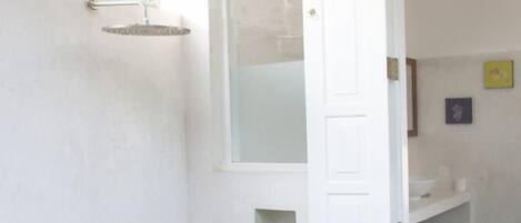 Un baño con ducha, toallero y puerta que da a otra habitación.