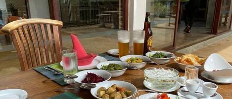 A dining table set with various dishes, drinks, and a bottle of beer.
