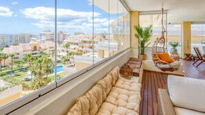 A balcony with a view of a residential area, a hanging chair, and a cushioned seating area. - 3-bedroom duplex with communal pools and Wi-Fi in Estepona (Estepona)