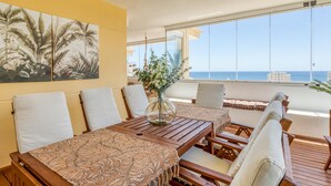 A dining area with a wooden table and chairs, a large window with a view of the sea, and a tropical-themed wall painting. - 3-bedroom duplex with communal pools and Wi-Fi in Estepona (Estepona)