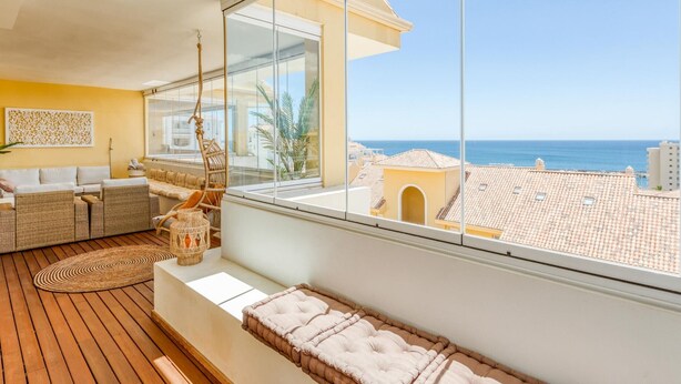 A balcony with wicker furniture, a cushioned bench, and a view of the sea. - 3-bedroom duplex with communal pools and Wi-Fi in Estepona (Estepona)