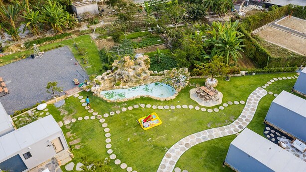 An aerial view of a landscaped property with a swimming pool, a rock feature, and a circular walking path.