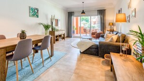 A modern living room with a dining area, a sofa set, a coffee table, and a TV mounted on the wall.