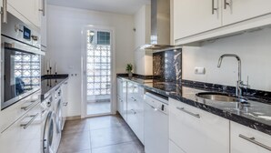 A modern kitchen with white cabinets, a stainless steel sink, and a built-in oven.