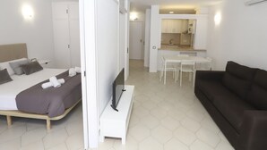 A modern hotel room with a bed, a desk, and a sofa.
