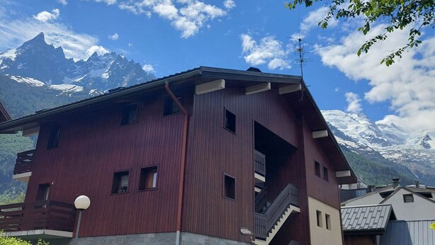 A red building with a balcony and a mountain view.