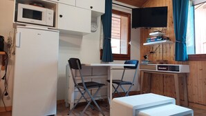 A compact kitchen with a microwave, refrigerator, and a small dining area with a table and chairs.