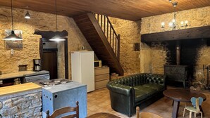 Una cocina rústica con pared de piedra, techo de madera y estufa empotrada.