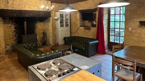 Una cocina rústica con pared de piedra, techo de madera, estufa empotrada, mesa de comedor y sofá de cuero.