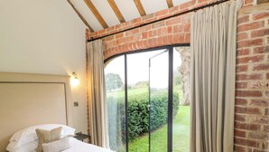 A bedroom with a large bed, a headboard, a nightstand, and a window with curtains. - The Carthouse (Ledbury)
