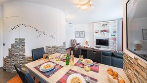 Un comedor con pared de piedra, televisor y estantería.