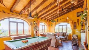 Een pooltafel in een kamer met grote ramen, houten balken en een gezellige zithoek.