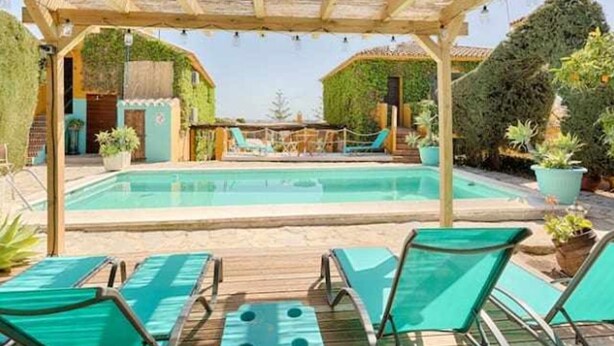 Een zwembad met ligbedden en een pergola.