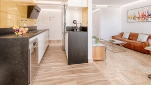 Una cocina moderna con horno empotrado y un comedor con sofá de cuero marrón y mesa de centro de vidrio.