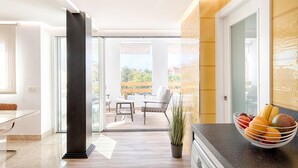 Una cocina moderna con encimera de mármol, un frutero y vistas al balcón.