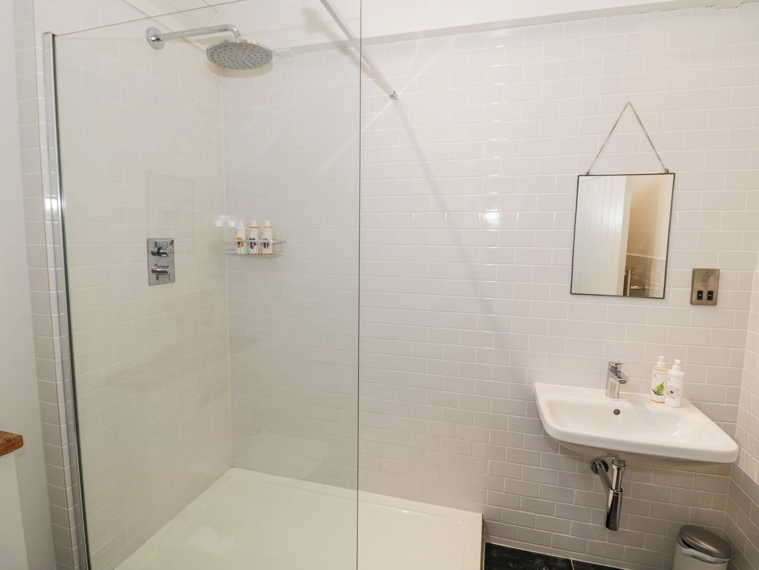 Un baño con ducha de vidrio, lavabo blanco y espejo.