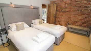 A hotel room with two beds, a brick wall, and a bench.