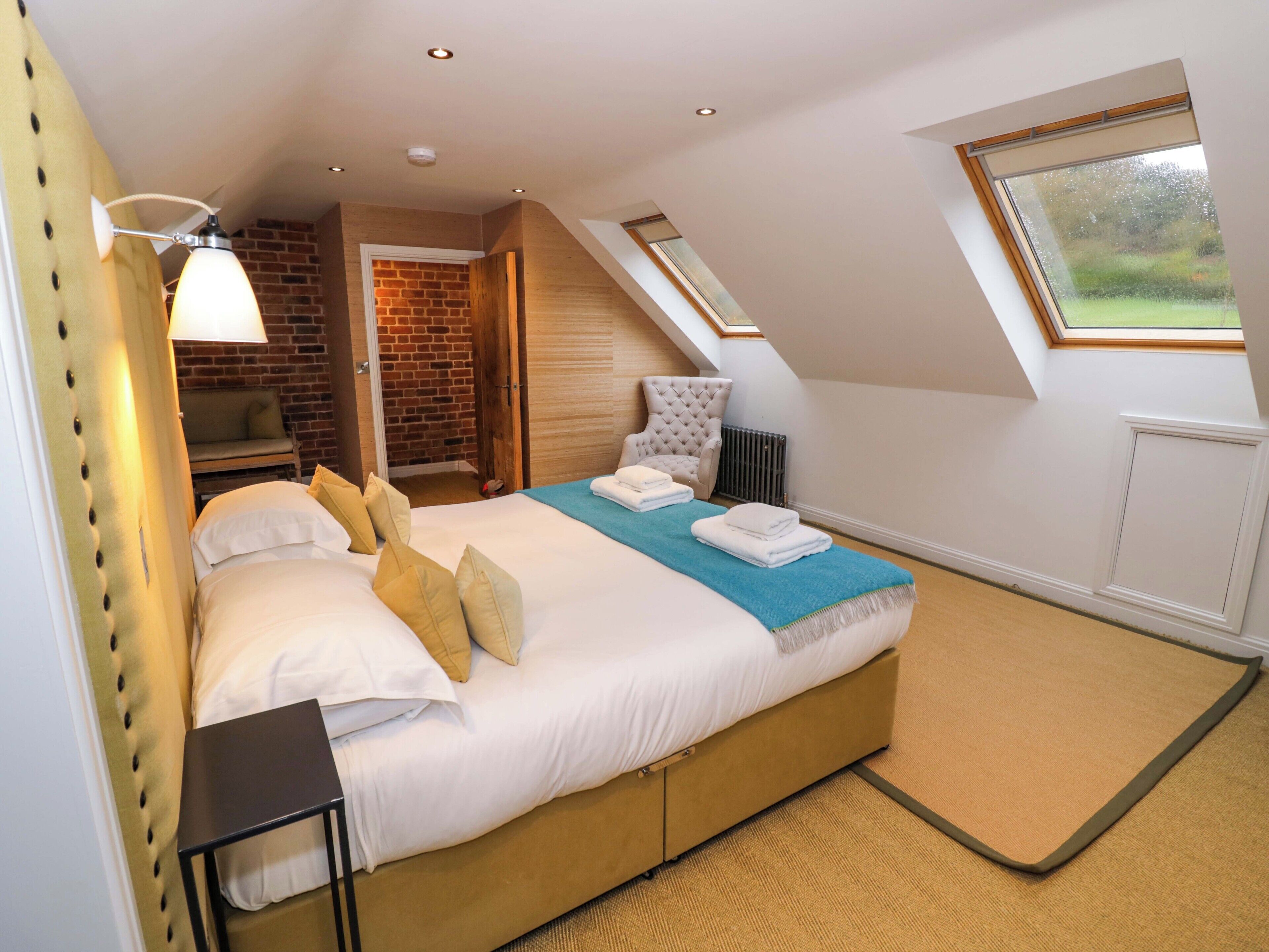Ein Schlafzimmer mit einem Bett, einem Sessel, einer Lampe, einer Heizung und einem Fenster.