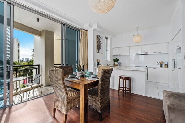 A modern apartment with a dining area, kitchen, and balcony.