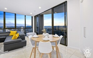 Relax in a spacious living area with expansive city and mountain views, a sofa, and a small dining table.
