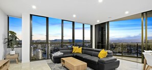 Relax in a spacious living room with a large sofa, floor-to-ceiling windows, and a city view.