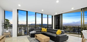 Relax in a spacious living room with a large sofa, floor-to-ceiling windows, and a city view.