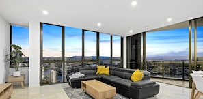 Relax in a spacious living room with a large sofa, floor-to-ceiling windows, and a city view.