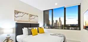 Relax in a spacious room with a large bed, framed artworks, and a city view.