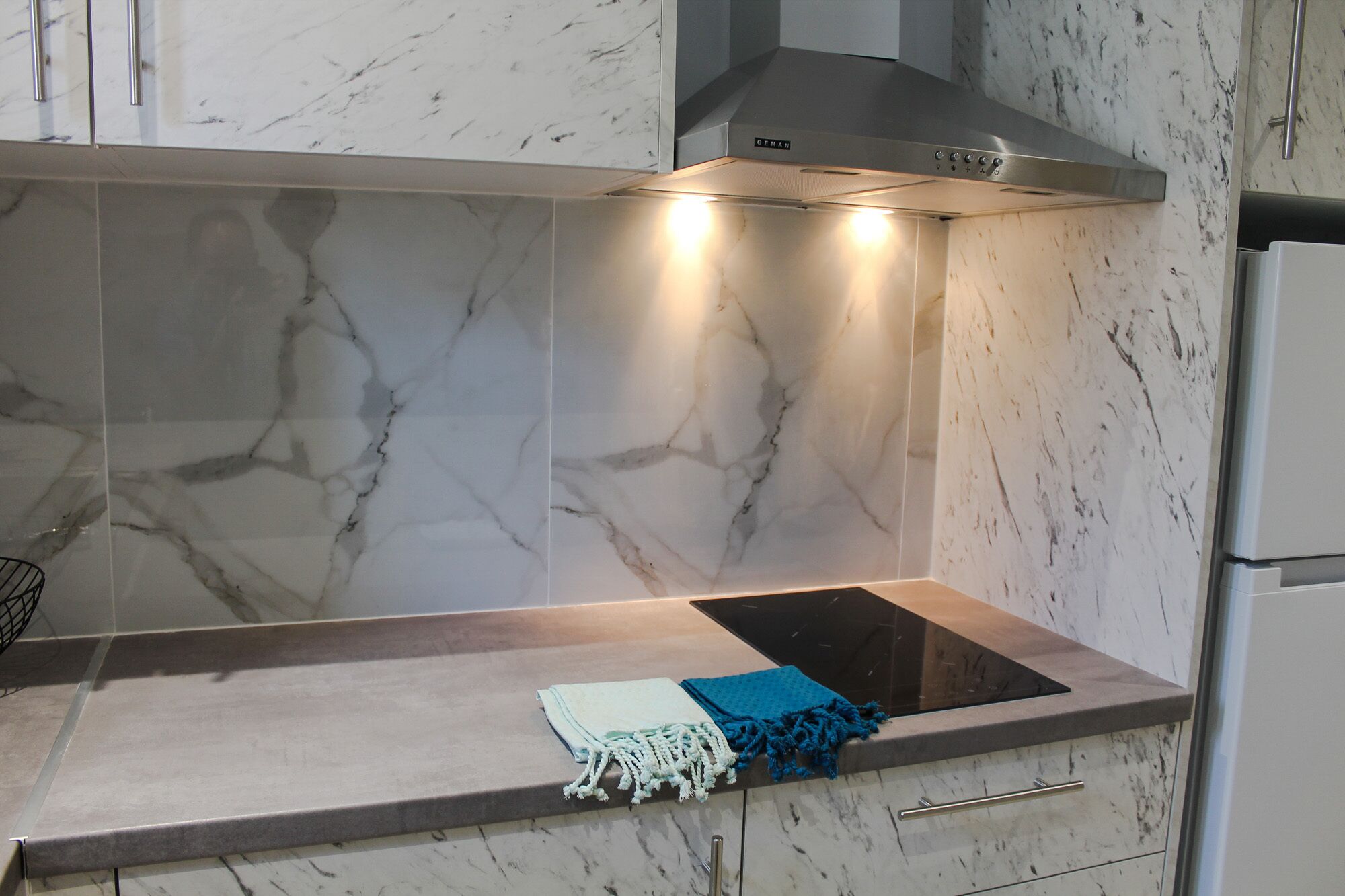 A kitchen with a built-in stove, a range hood, and marble tiles.