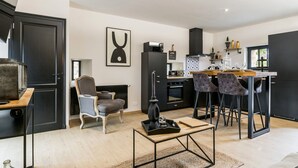 Una cocina moderna con comedor, que incluye un taburete de bar, una silla y una mesa con una bandeja.