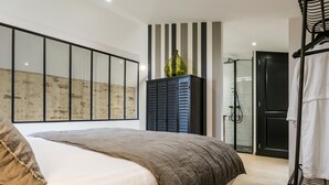 Un dormitorio moderno con una cama grande, un armario, zona de ducha y vistas al exterior.