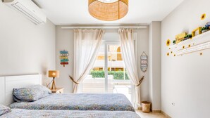 A bedroom with a bed, a lamp, a wall with signs, and a view of the outside.