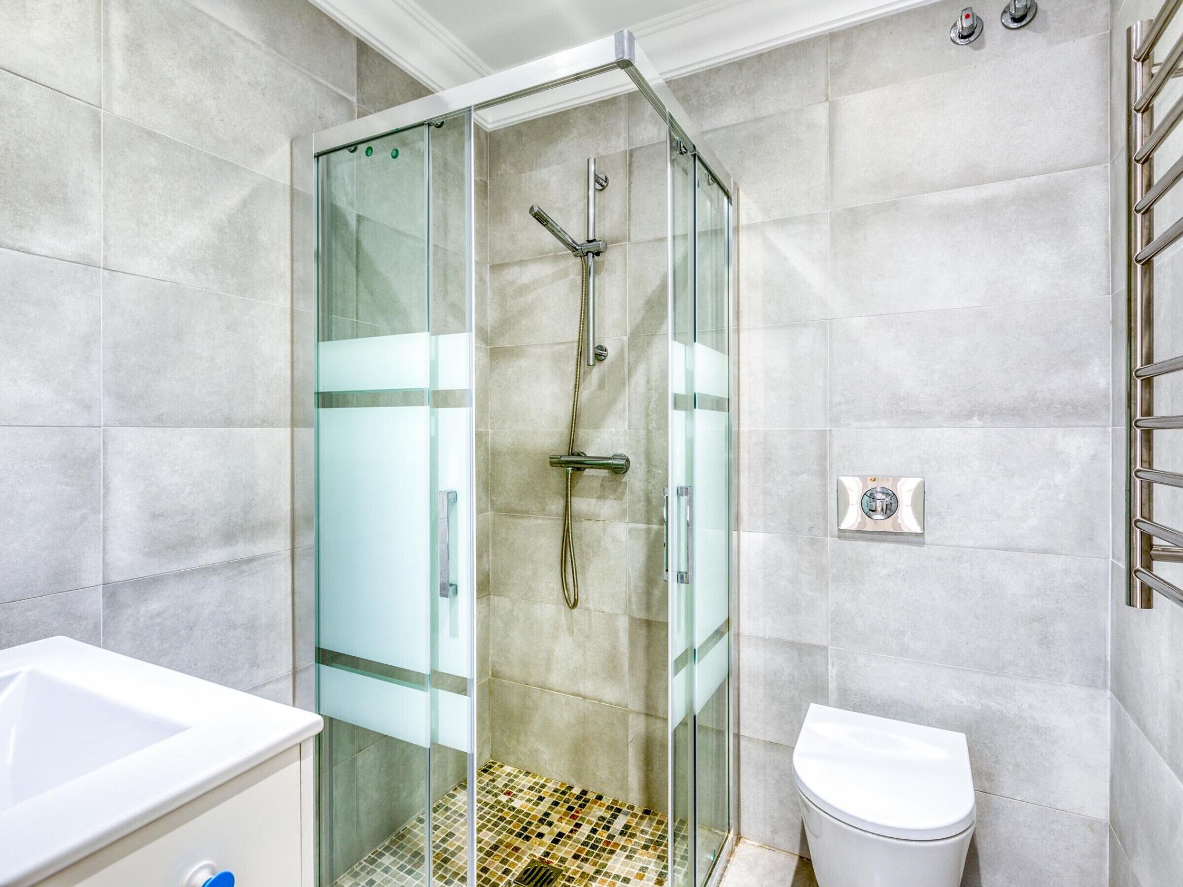 Une salle de bain moderne avec une douche à parois de verre, un lavabo blanc et des toilettes.