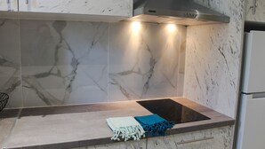 A kitchen with a built-in stove, a range hood, and marble tiles. - Stylish First Floor Two Bedroom Flat in Kassiopi with Breakfast (Κασσιόπη)