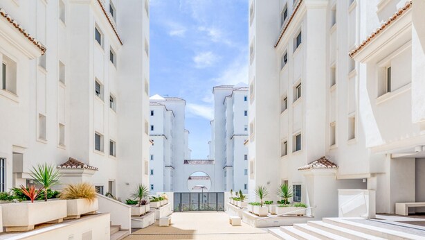Un edificio moderno con un patio central, caracterizado por un diseño simétrico, paredes blancas y techos de tejas.