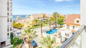 Zona residencial con piscina, palmeras y vista al mar.