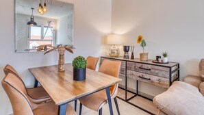 Un comedor moderno con una mesa de madera, sillas y un espejo encima.