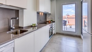 Una cocina moderna con horno integrado, lavavajillas y un amplio ventanal con vistas a la ciudad.