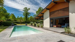 Et moderne hus med swimmingpool, overdækket terrasse og velplejet have.