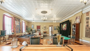 A spacious room with a pool table, a billiards table, and a bar area.
