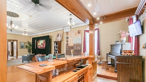 A spacious living area with a wooden bar, a piano, and a television.
