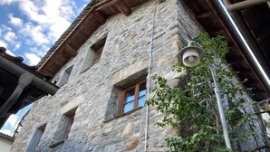 A stone building with a wooden roof, a visible window, and a street lamp.