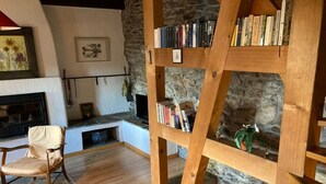 A cozy living room with a stone fireplace, wooden bookshelves, and comfortable seating.
