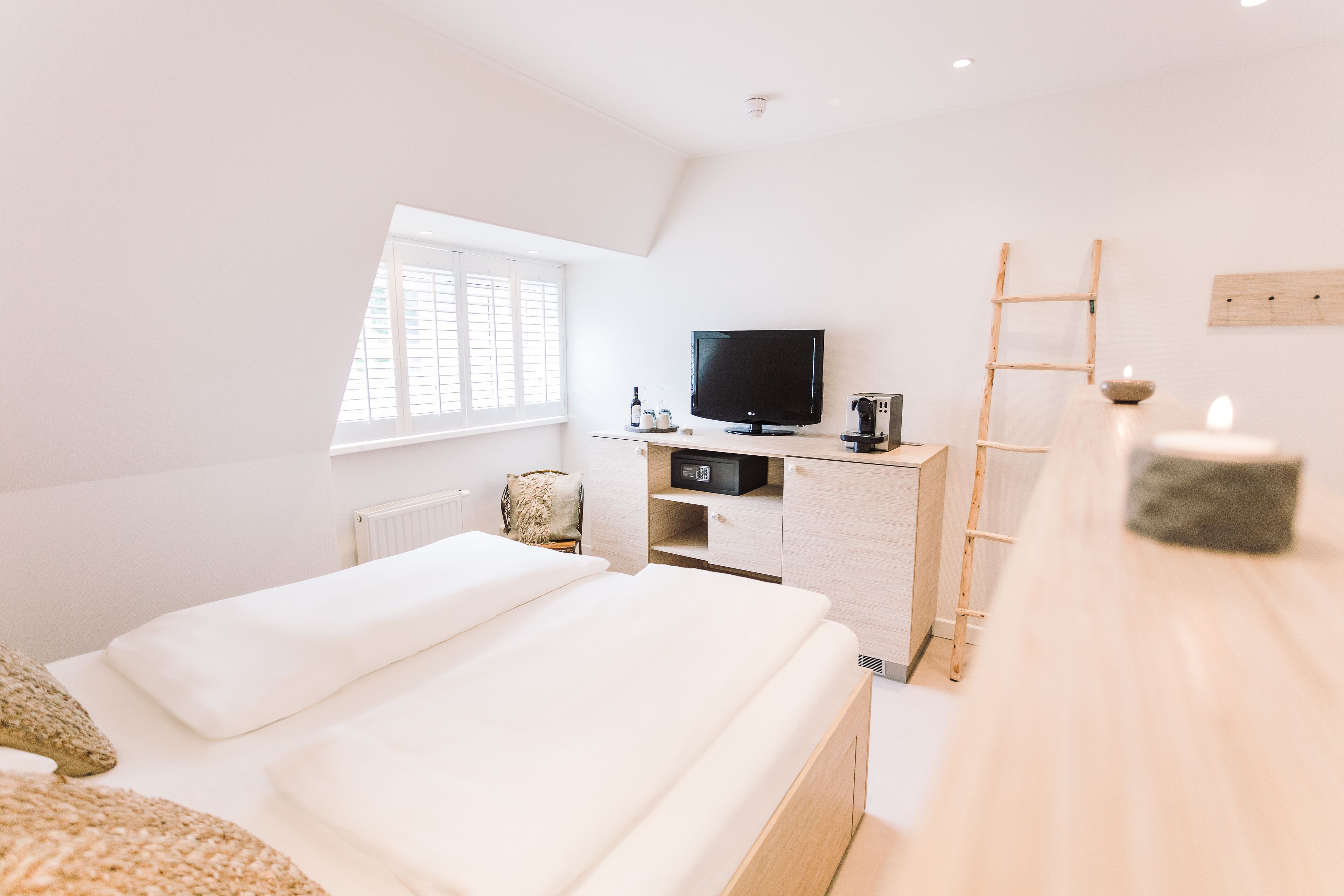 Een moderne slaapkamer met twee bedden, een televisie, een bureau en een raam.