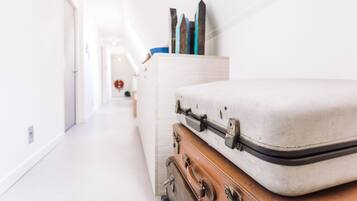 Um corredor com uma fileira de malas e um aparador com objetos decorativos.